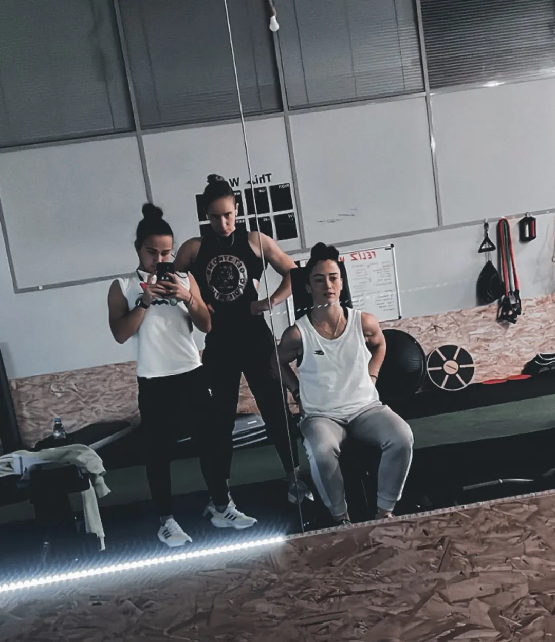 Três atletas ao espelho na zona de treino funcional do estúdio